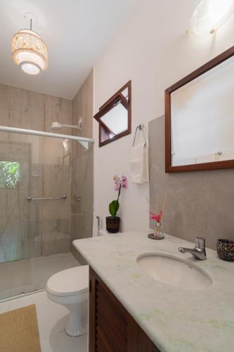 a bathroom with a sink and a toilet and a mirror at Pousada Samambaia in Trancoso
