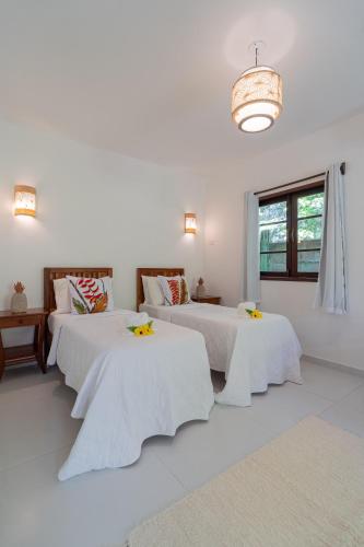 a white room with two beds and a window at Pousada Samambaia in Trancoso