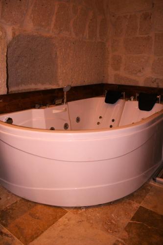 a white bath tub in a room with a stone wall at Timur inn Cappadocia in Goreme