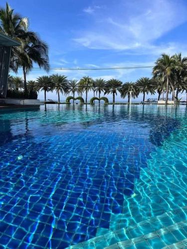 a blue swimming pool with palm trees in the background at Seaview Jomtien Floor16 ห้องวิวทะเล 33sqm in Jomtien Beach