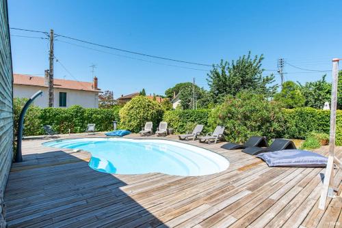 une piscine sur une terrasse en bois avec des chaises autour dans l'établissement Villa Olympe, à Montauban