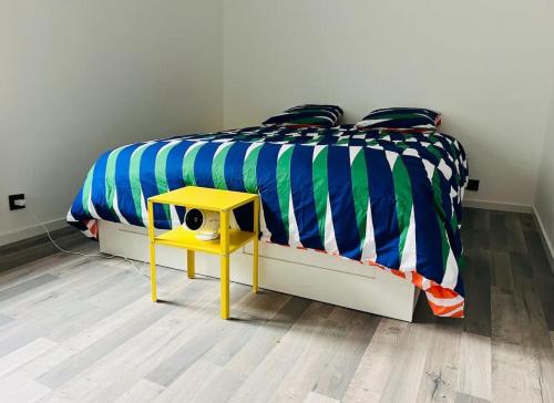 - une chambre avec un lit et une table jaune dans l'établissement Appartement d'Exception à Saint-Étienne Spacieux 100m2 Haut de Gamme avec 2 Chambres, à Saint-Étienne
