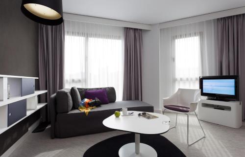 a living room with a couch and a tv and a table at Novotel Suites Malaga Centro in Málaga
