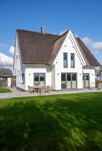 a white house with a picnic table on a lawn at Ferienhaus Reethauszeit in Dranske