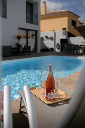 a bottle of wine and glasses on a tray next to a swimming pool at Portugal Alma Villa Algarve - Luxury Villa with Private Pool in Alcantarilha