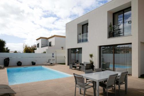 a house with a swimming pool and a table and chairs at Portugal Alma Villa Algarve - Luxury Villa with Private Pool in Alcantarilha