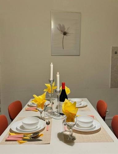 une table à manger avec des assiettes blanches et des bougies dans l'établissement Hyper Centre Krutenau Étoile Bourse Appart, à Strasbourg