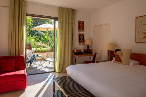 a bedroom with a bed and a woman sitting on a patio at Hôtel 96 in Marseille