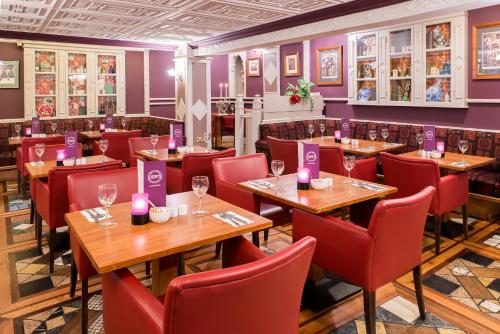 a restaurant with wooden tables and red chairs and purple walls at River Island Hotel in Castleisland
