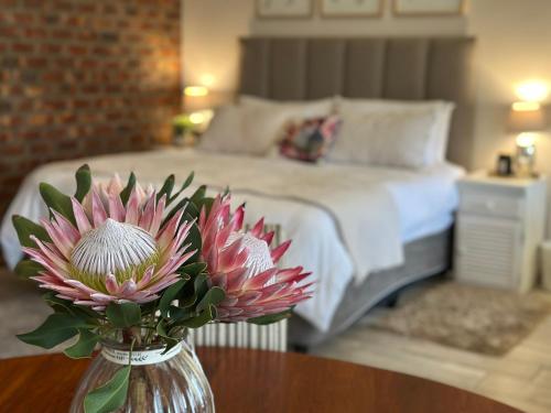 a vase with flowers on a table in a bedroom at Piekfijn Robertson in Robertson