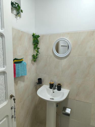 a bathroom with a white sink and a mirror at Plateau Bedroom & Chambre - Praia Center 1 in Praia