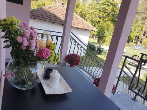 a table with a vase of flowers on a balcony at Vila Lela in Vrnjačka Banja
