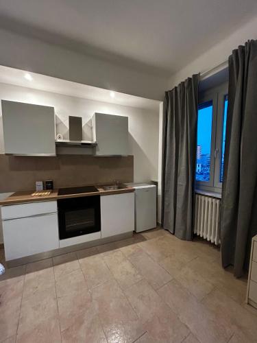 een keuken met witte kasten en een groot raam bij Monolocale 1 in Turijn
