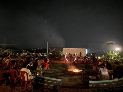 a crowd of people sitting around a fire pit at night at Mowgli's Cafe Hampi & Guest House in Hampi