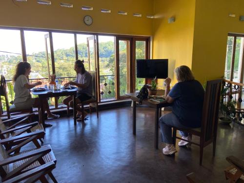 a group of people sitting at tables in a room with windows at Sesatha lake Kandy in Kandy
