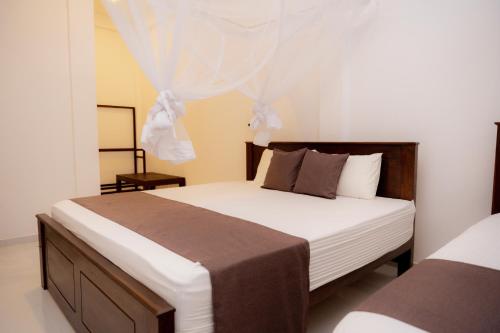 a bedroom with a large bed with white sheets at Sea Bay Inn Tangalle in Tangalle