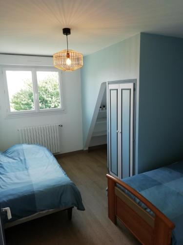 une chambre avec un lit, une fenêtre et un lustre dans l'établissement Maison familiale pour un agréable séjour, à Donville-les-Bains