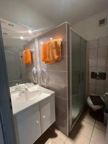 La salle de bains est pourvue d'un lavabo, d'une douche et de serviettes orange. dans l'établissement Les villas Maristella, Argentu, à Aregno