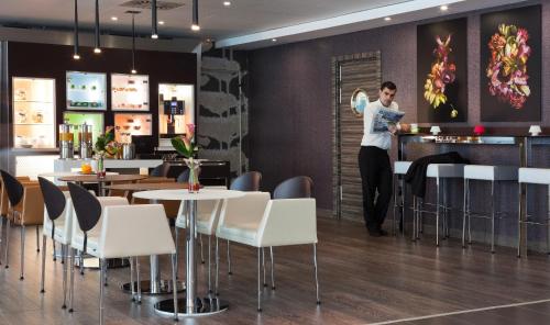 a man standing at a bar in a restaurant at Novotel Suites Malaga Centro in Málaga