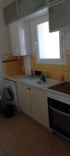 une petite cuisine avec un évier et une fenêtre dans l'établissement Maison La p'tite pause, à Piolenc