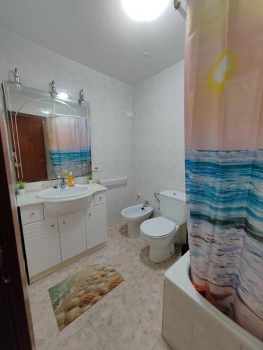 a bathroom with a sink and a toilet and a shower curtain at Vacances à la plage in Puerto de Sagunto