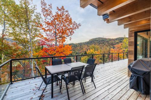 a wooden deck with a table and chairs on it at Le Harfång - Vue imprenable - Sauna - 3min du Mont in LʼAnse-Saint-Jean