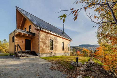 a house in the woods with autumn foliage at Le Harfång - Vue imprenable - Sauna - 3min du Mont in LʼAnse-Saint-Jean