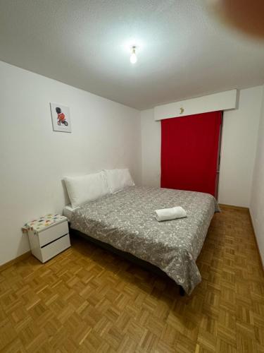 a small bedroom with a bed and a red door at La Maison de Voyage in Lausanne