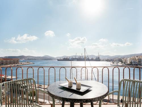 a table and chairs on a balcony with a view of the water at Igisó in Ermoupoli