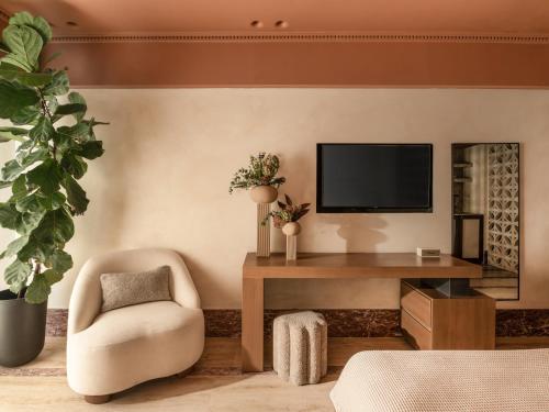 a living room with a chair and a television at Igisó in Ermoupoli