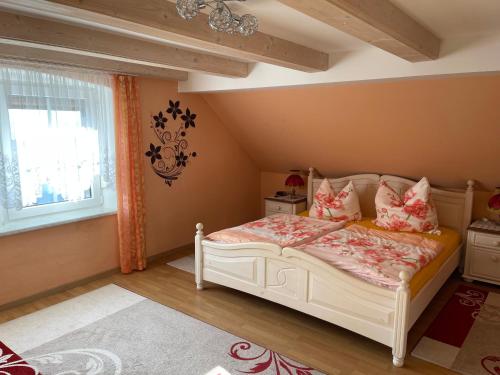 a bedroom with a white bed with pillows and a window at Ferienhaus Ochsenkopfblick in Fichtelberg