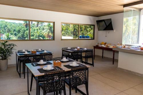 a dining room with tables and chairs and windows at Aconchego Dona Quita in São Miguel dos Milagres