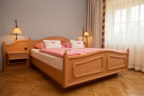 a bedroom with a large wooden bed with pink sheets at Perbersdorfer Heuriger in Neuhofen an der Ybbs