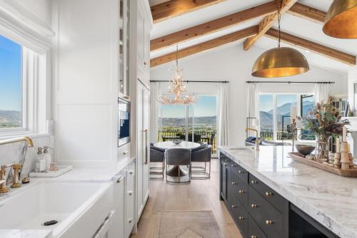 una cucina con banconi bianchi e un tavolo con sedie di New Mountain Luxury and Wellness Retreat Full Home a Eden
