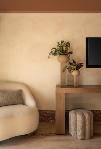 a living room with a couch and two vases with flowers at Igisó in Ermoupoli