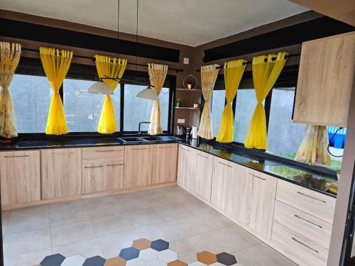 a kitchen with yellow drapes on the windows at Très belle villa avec piscine in Foulpointe