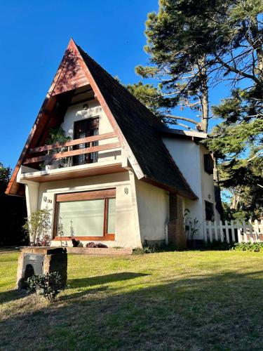 ein kleines weißes Haus mit einem Gameradach in der Unterkunft Makikihi - Barrio Norte in Villa Gesell