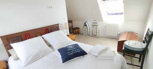 a bedroom with a white bed with a blue pillow at Coeur de granit rose, meublé alliant le charme de l'authentique breton et du confort, classé 3 étoiles, à 5mn de 13 plages de la réputée cote de granit rose in Trégastel