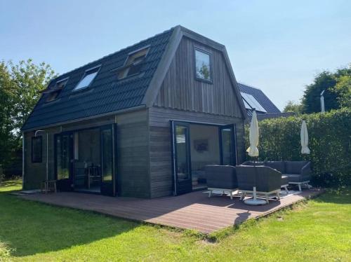 a small house with a deck and some chairs at Duinhuis Zout Hout in Egmond-Binnen