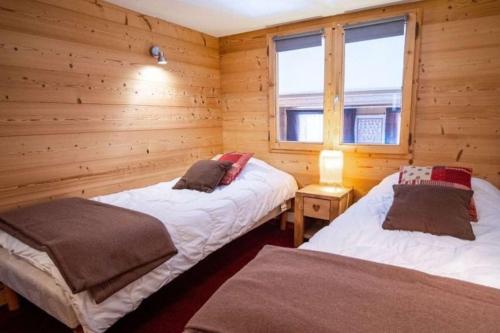 deux lits dans une chambre aux murs en bois dans l'établissement Appartement duplex-mezzanine, à Val Thorens