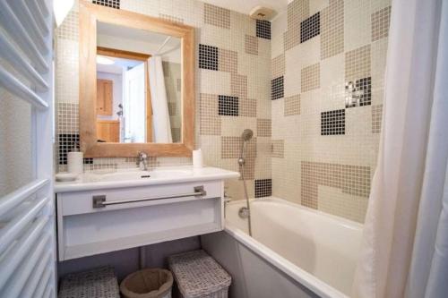une salle de bain avec un lavabo, une baignoire et un miroir dans l'établissement Appartement duplex-mezzanine, à Val Thorens