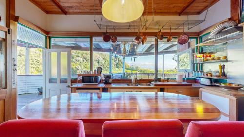 a large kitchen with a wooden table and red chairs at Bluff Hill Lighthouse B&B in Napier