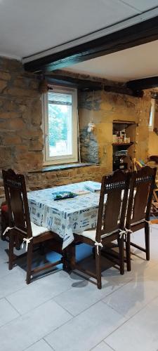 une table à manger avec deux chaises et un mur en pierre dans l'établissement Coeur de granit rose, meublé alliant le charme de l'authentique breton et du confort, classé 3 étoiles, à 5mn de 13 plages de la réputée cote de granit rose, à Trégastel