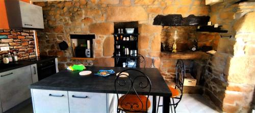 a kitchen with a counter and a stone wall at Coeur de granit rose, meublé alliant le charme de l'authentique breton et du confort, classé 3 étoiles, à 5mn de 13 plages de la réputée cote de granit rose in Trégastel