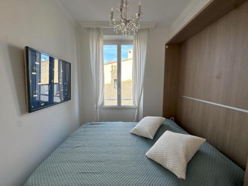 - une chambre avec un lit, un lustre et une fenêtre dans l'établissement Le cœur de Cannes, à Cannes