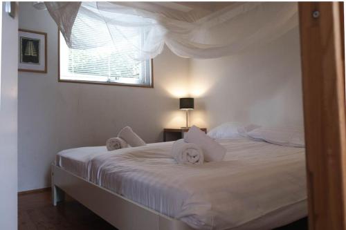 a bedroom with a bed with white sheets and a window at Vakantiewoning MV8 in Egmond-Binnen