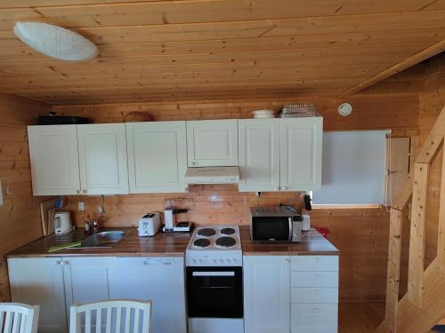 a kitchen with white cabinets and a stove top oven at Lomamökki seitsemisen kansallispuiston lähellä in Parkano