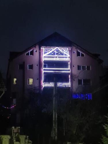 a building with lights on the side of it at night at Vila Muntii Bucegi & SPA in Bran