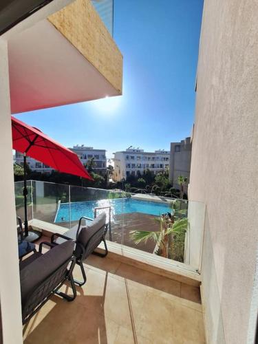 a balcony with two chairs and an umbrella and a pool at Appartement piscine front de mer in Mohammedia