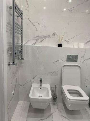 a white bathroom with a toilet and a sink at Coliseum Palace Panorama View in Chişinău